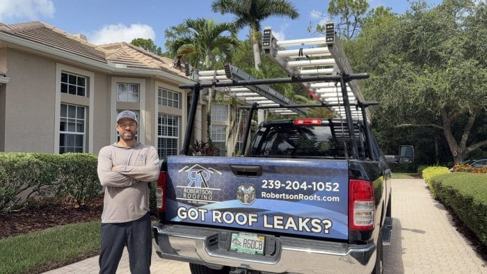 Owner of Robertson Roofing standing next to his truck in front of a newly repaired roof in Fort Myers, FL.