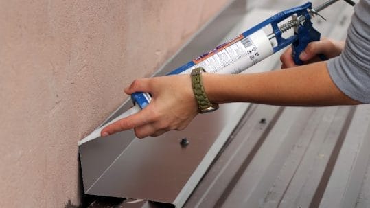 Applying silicone sealants for metal roof repair in Fort Myers, FL.
