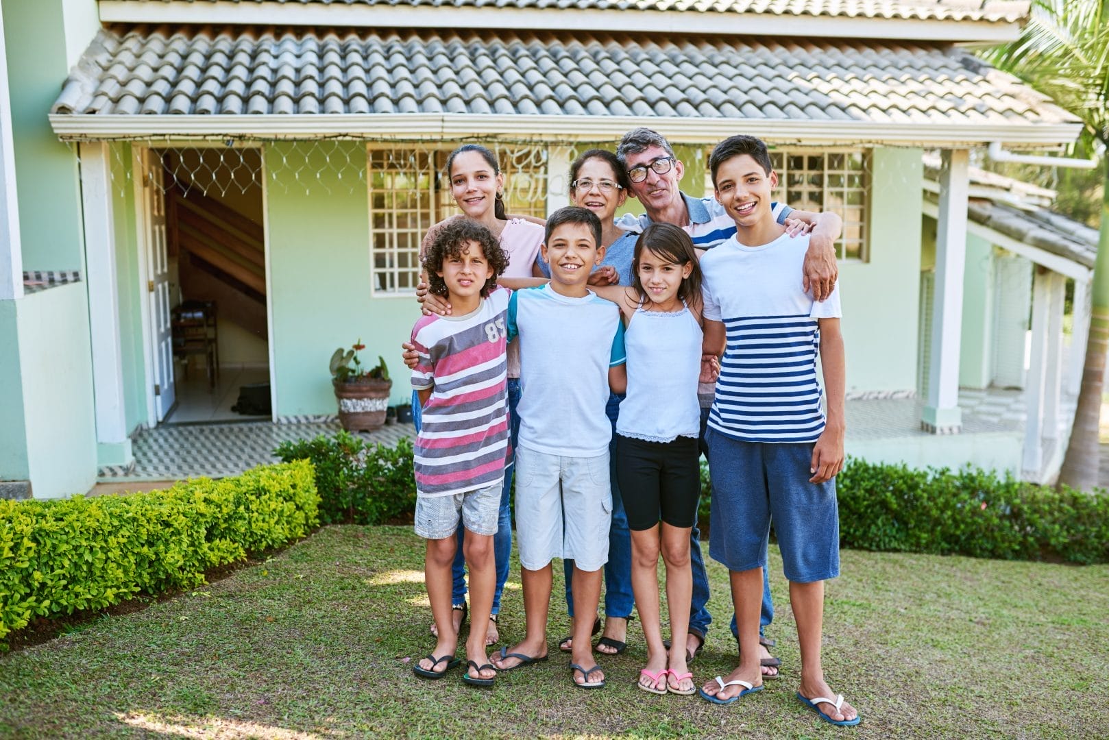 Family standing in front of their home with a newly repaired tile roof