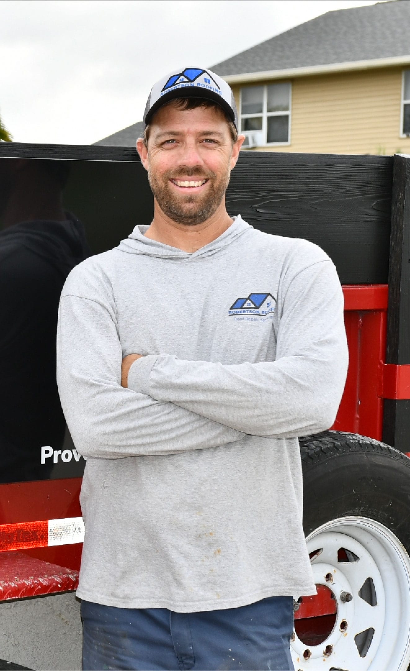Zac Robertson, founder of Robertson Roofs, smiling in front of his company truck